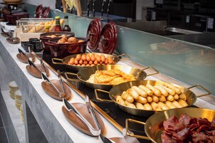 A buffet with various food items including fried eggs, sausages, and bacon.