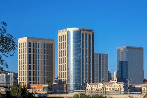 A modern high-rise building with a reflective glass facade, surrounded by other high-rise buildings in an urban setting.