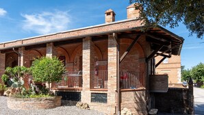 Un bâtiment en briques doté d’un patio couvert, de fenêtres en arc de cercle et d’une cour intérieure en gravier.