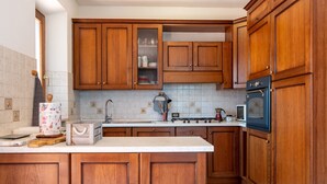 Une cuisine avec des meubles en bois, une cuisinière, un four à micro-ondes et un dosseret carrelé.