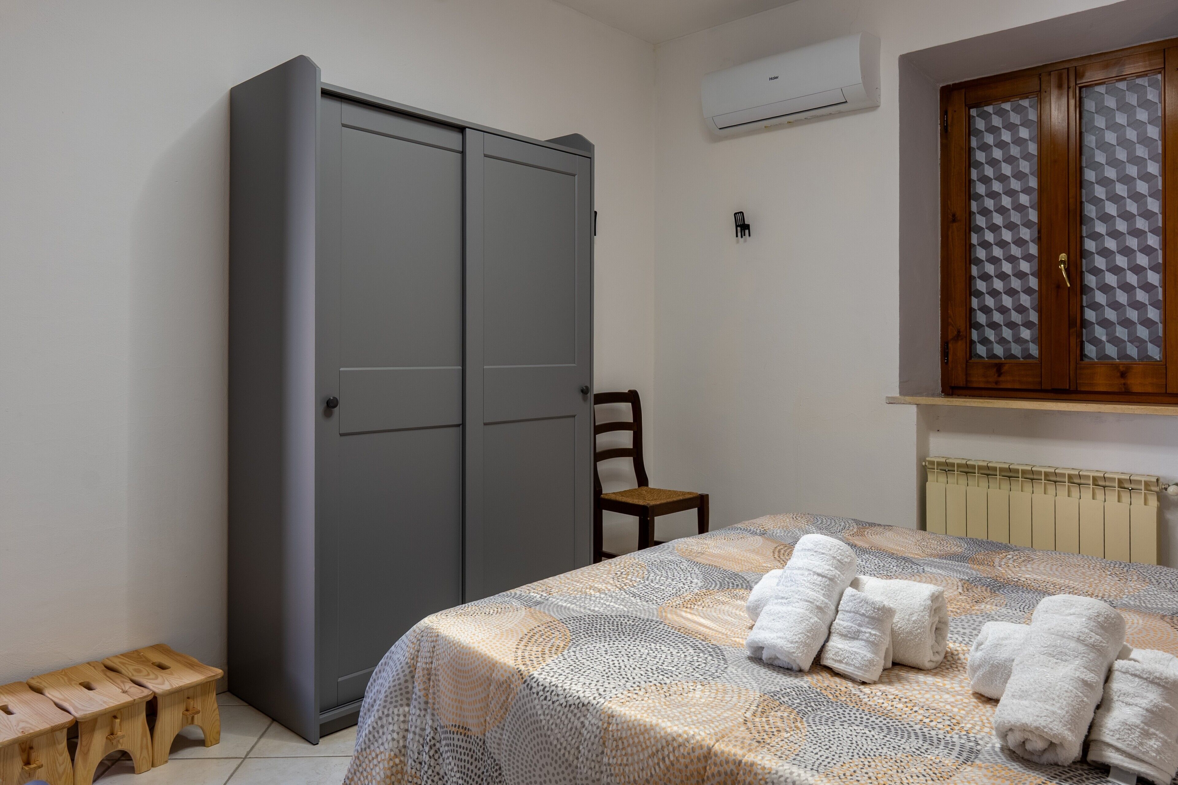 Une chambre à coucher avec un lit, une armoire, une chaise et une fenêtre.