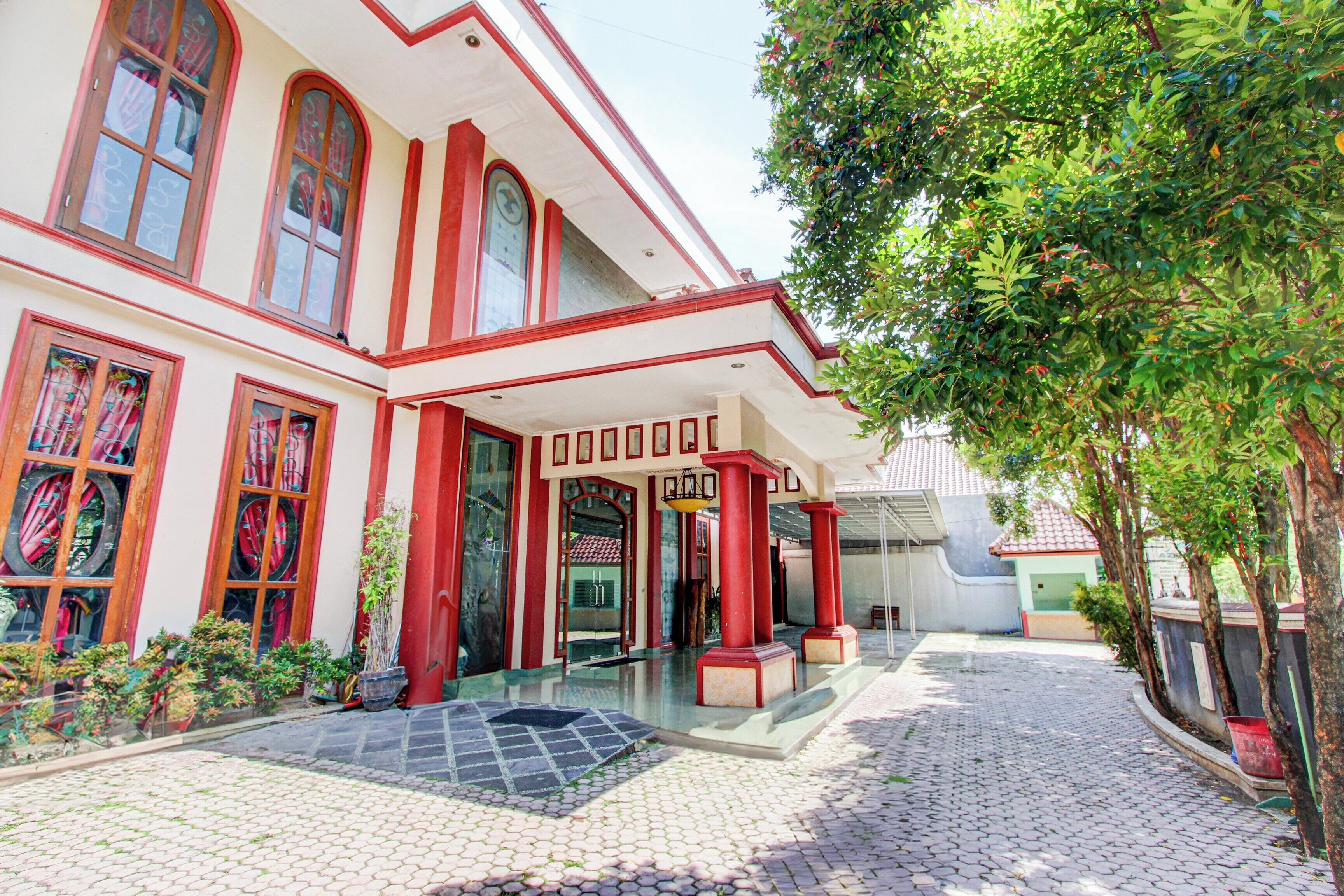 A building with a red and white facade, large windows, and a paved courtyard.