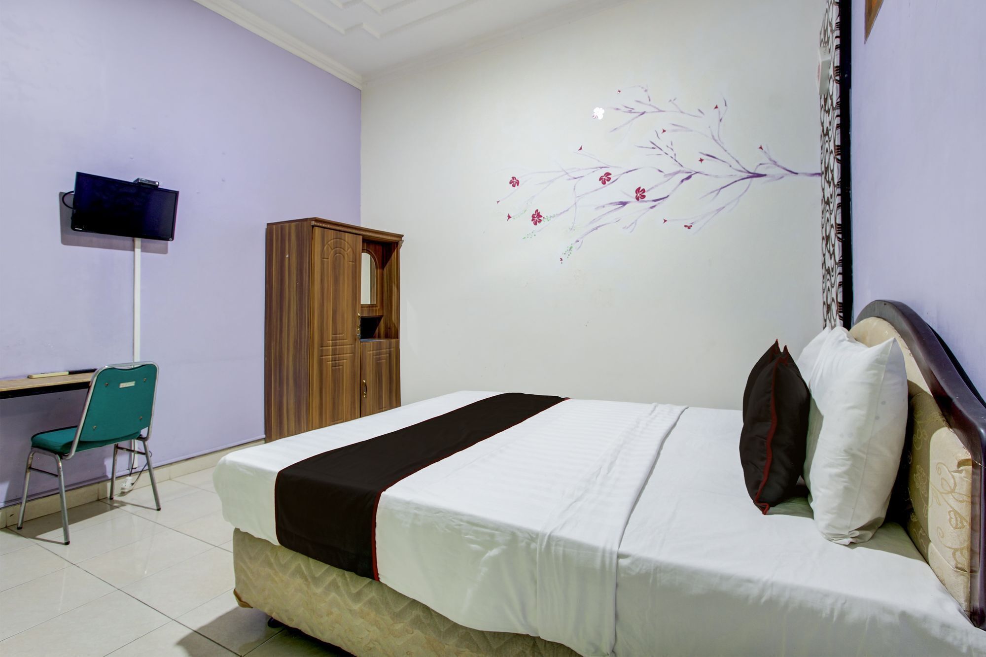 A hotel room with a bed, a desk, a chair, and a TV.