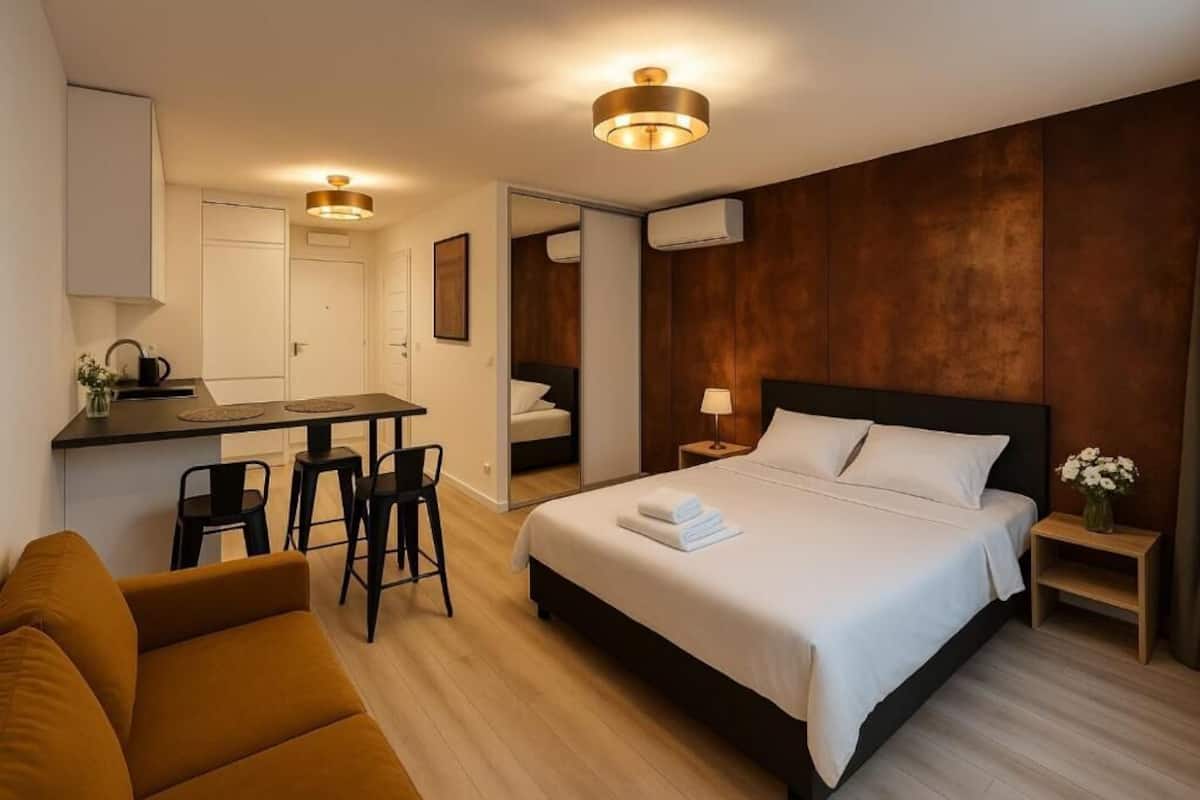 A hotel room with a bed, a desk, and a sofa.