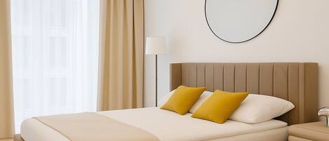 Una habitación de hotel moderna con una cama grande, una mesita de noche, una lámpara y un espejo redondo en la pared.