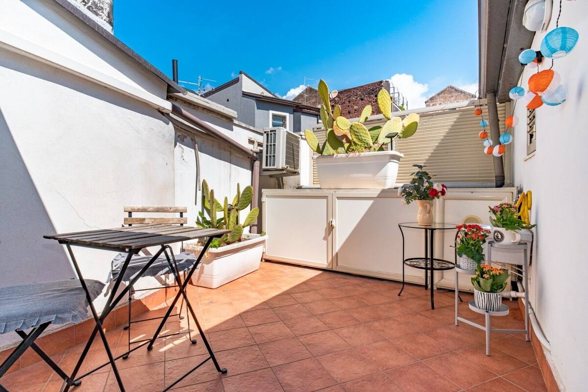 A small patio with a table, chairs, and potted plants.