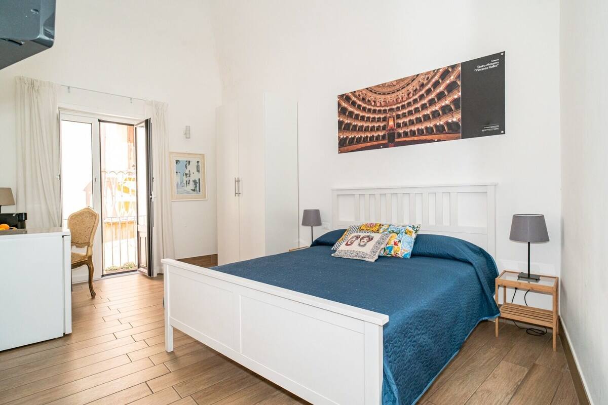 A bedroom with a bed, a desk, a chair, and a window.