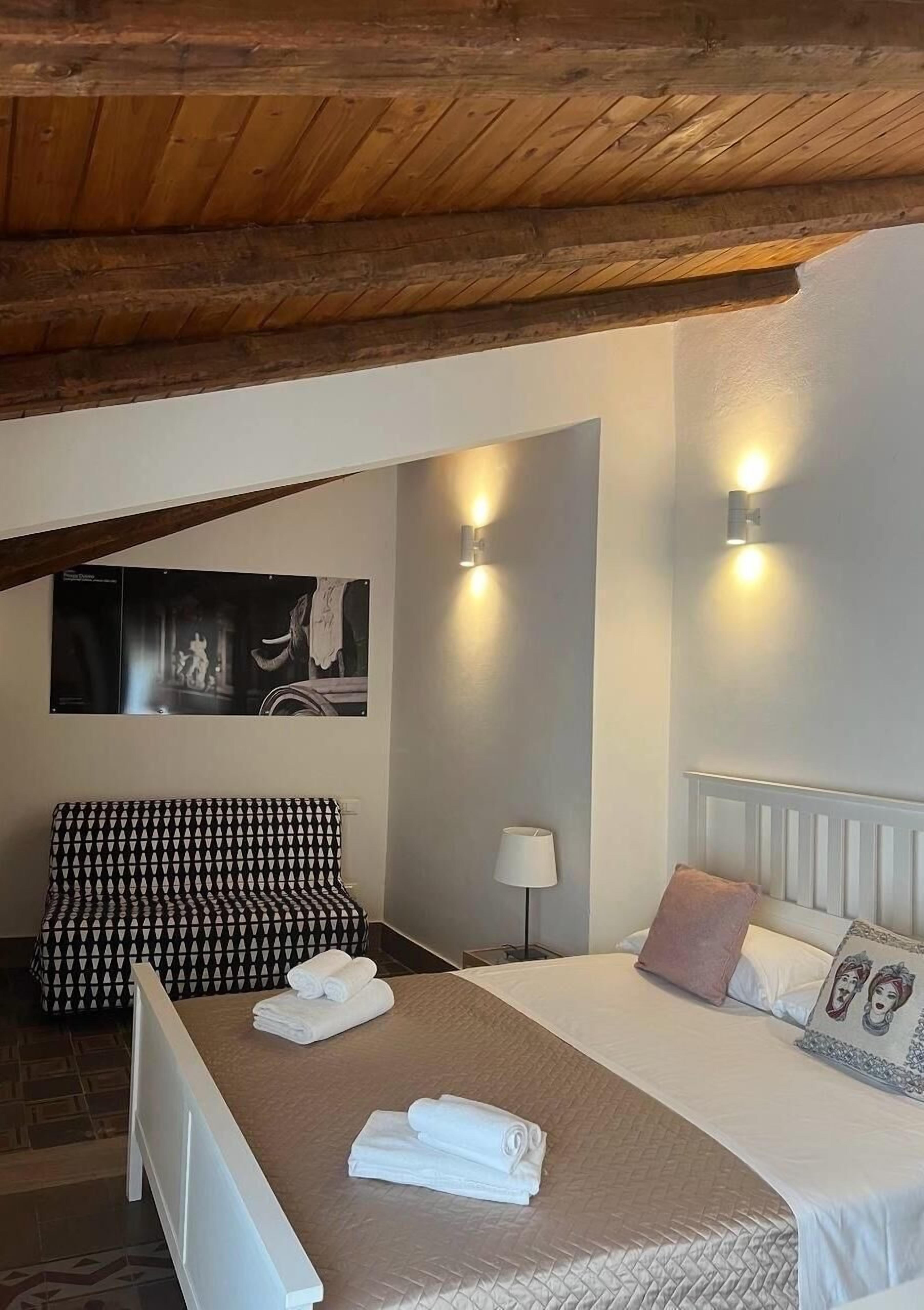 A cozy room with a bed, a patterned sofa, and a painting on the wall.