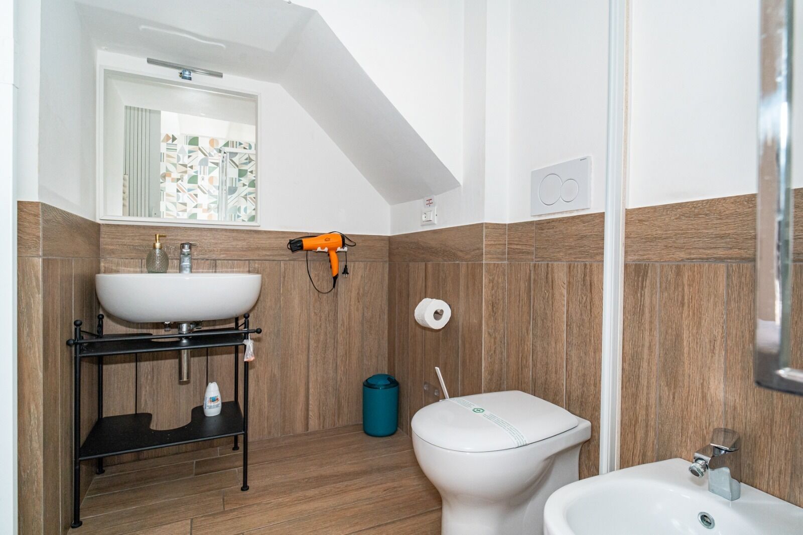 A modern bathroom with a white sink, a toilet, and a bidet.