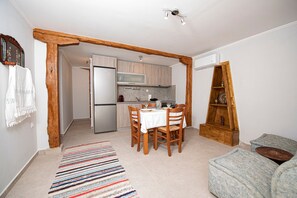 Cocina compacta con comedor, vigas de madera y una pequeña zona de estar.
