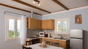 A compact kitchen with wooden cabinets, a microwave, a sink, and a refrigerator. - Holiday Home 'Lovely' with Balcony, Wi-Fi and Air Conditioning (Sivros)