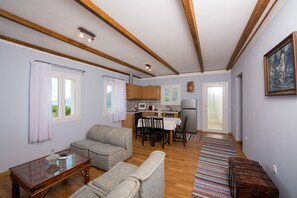 Sala de estar com sofá, mesa de centro, cozinha com micro-ondas e mesa de jantar com cadeiras.