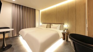 Quarto de hotel moderno com uma cama grande, uma mesa redonda, uma cadeira preta e uma banheira.