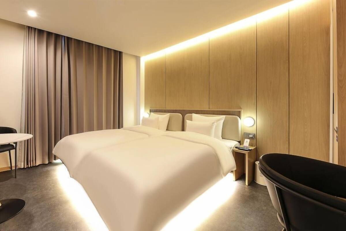 Ett modernt hotellrum med en stor säng, ett runt bord, en svart stol och ett badkar.