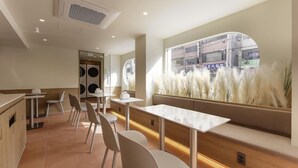 Um restaurante moderno com um balcão comprido, cadeiras brancas e uma grande janela com vista para a rua.