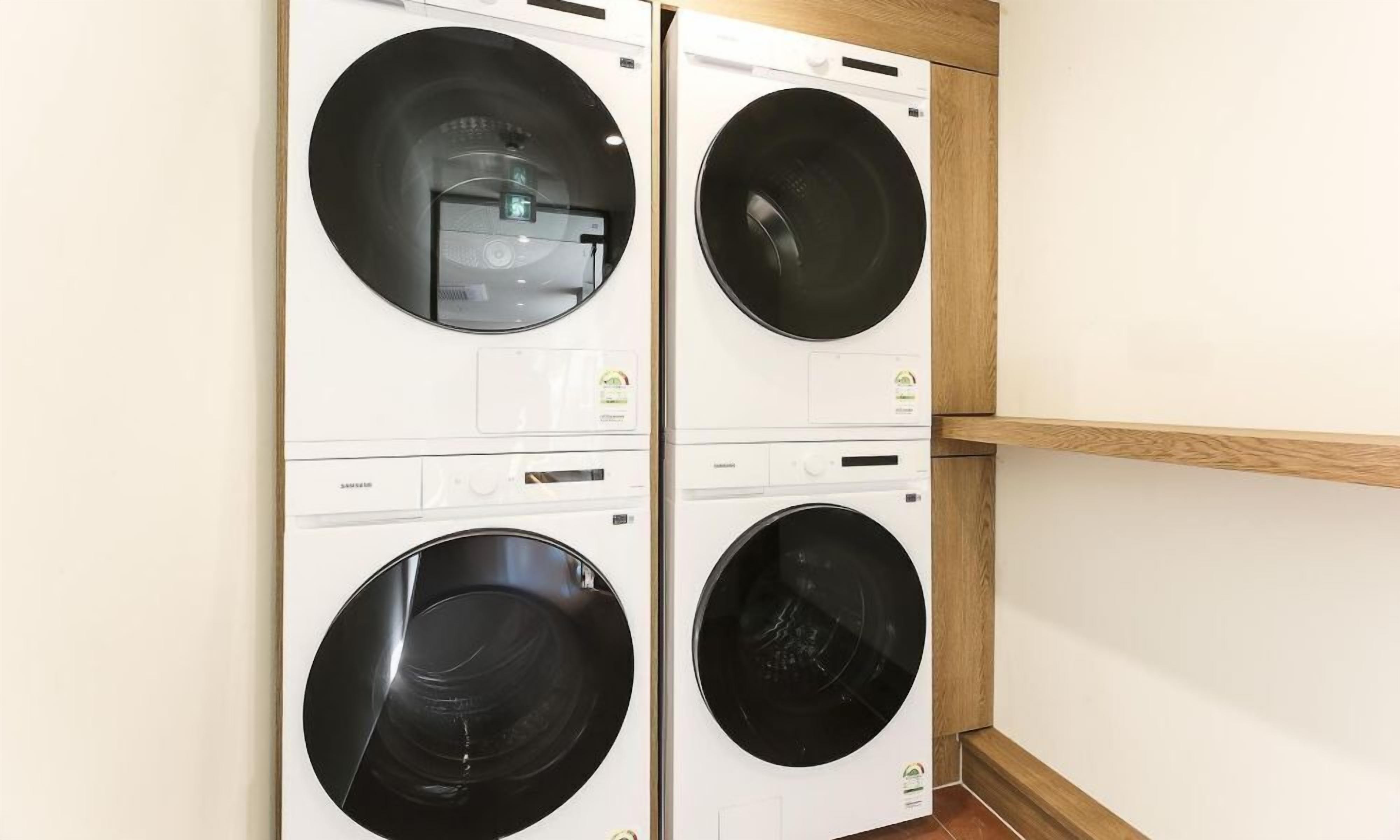 A laundry room with four front-loading washing machines.