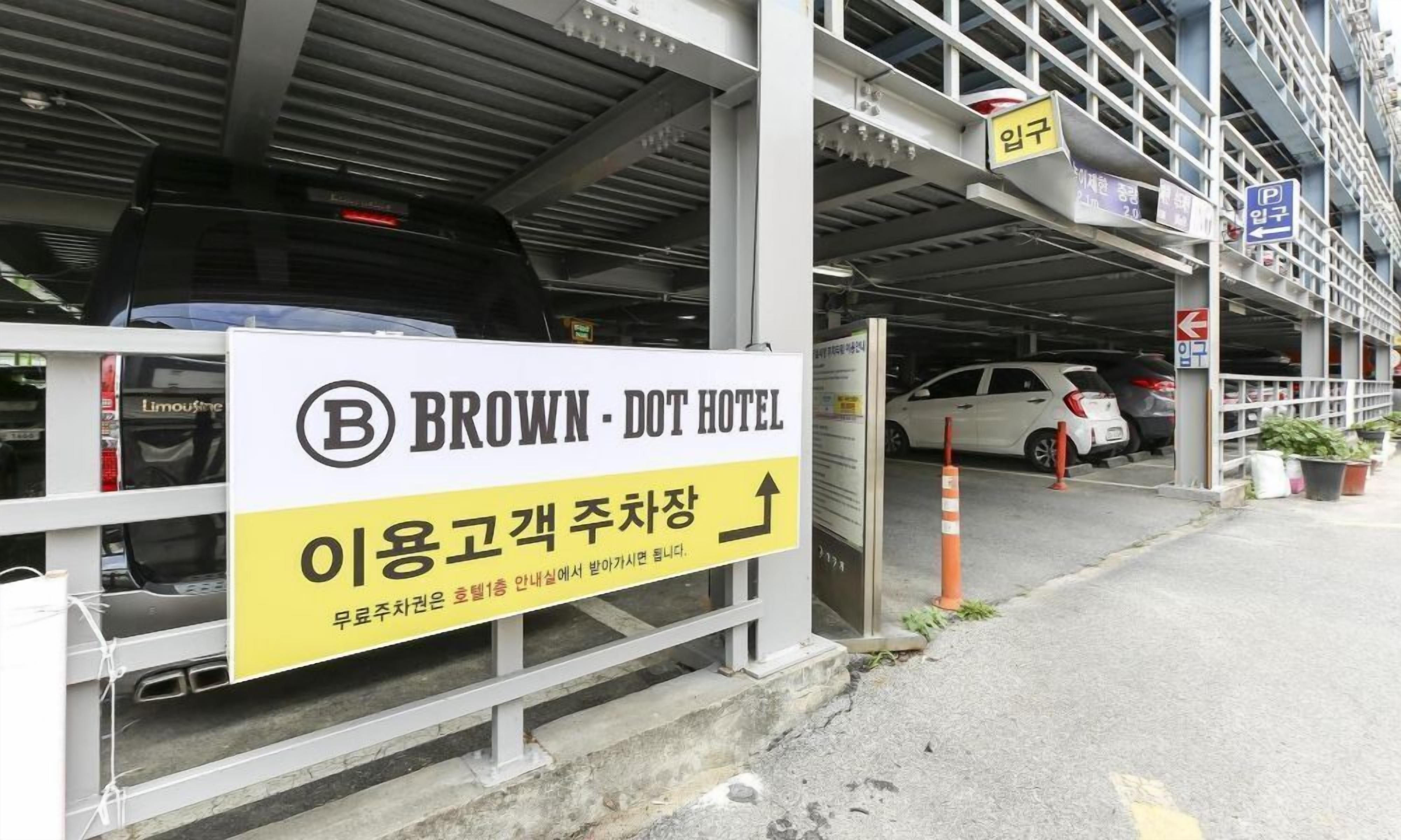 Entrada a un estacionamiento con un letrero para Brown-Dot Hotel y una flecha indicadora.