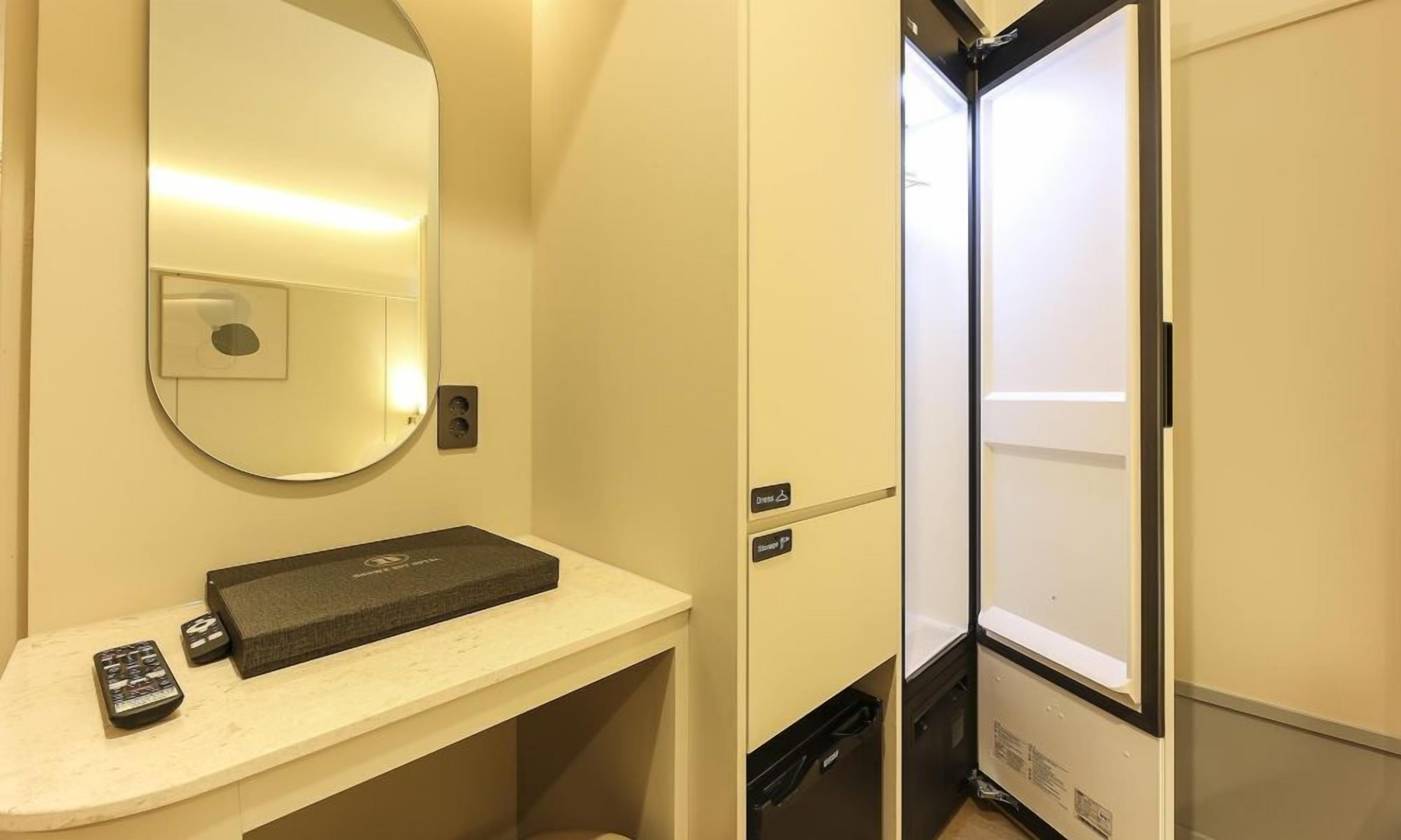 A compact bathroom with a mirror, a small sink, and a storage cabinet.