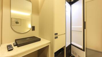 A compact bathroom with a mirror, a small sink, and a storage cabinet.