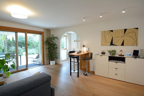 A modern kitchen with a dining area, a large window, and a potted plant.