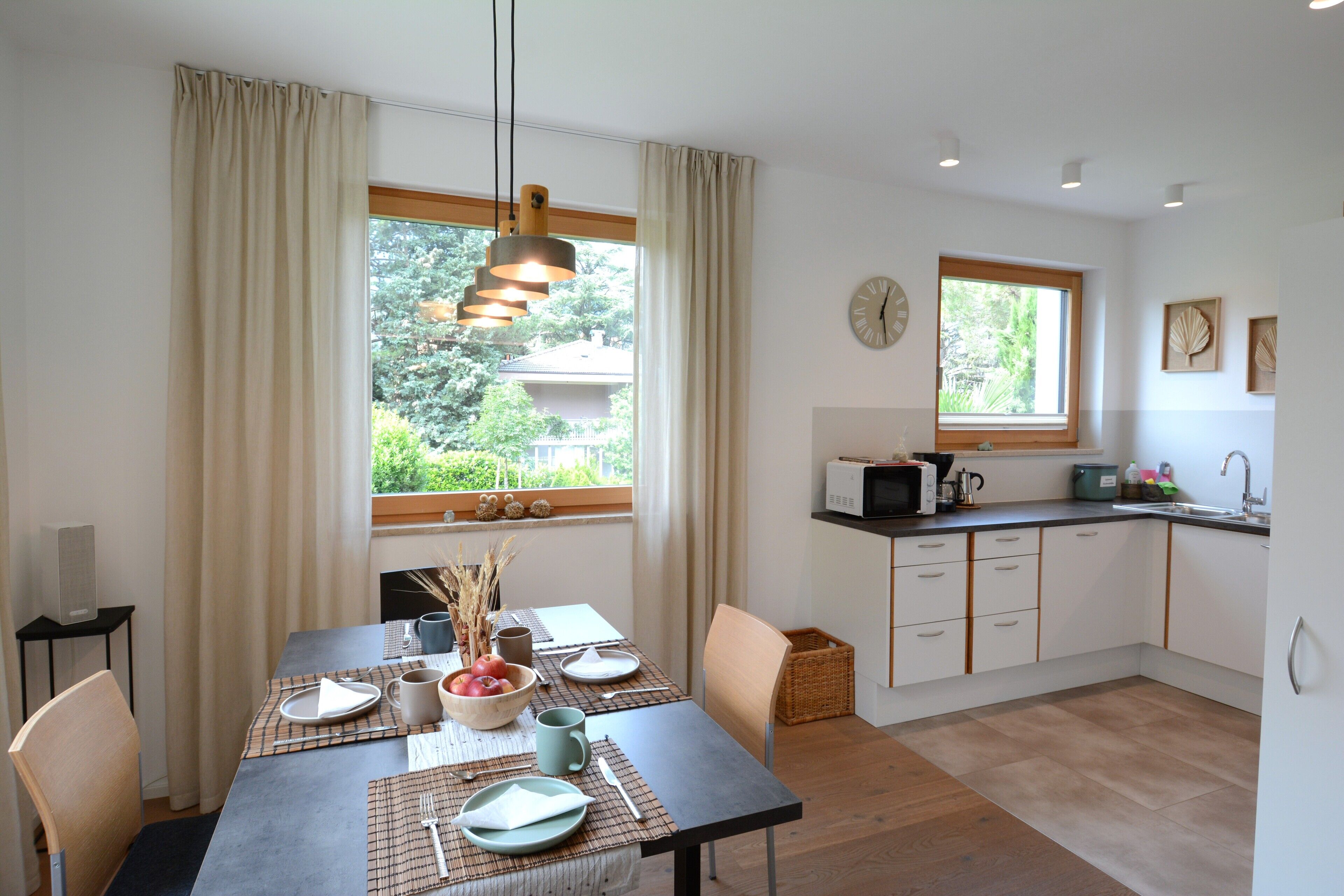 A modern kitchen with a dining area, featuring a large window, a microwave, and a sink.