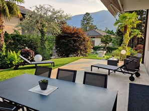 Um pátio com móveis de jardim, um jardim e vista para a montanha.