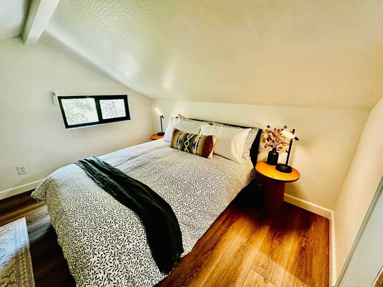 Un dormitorio con una cama, una mesita de noche y una pequeña mesa con lámpara.