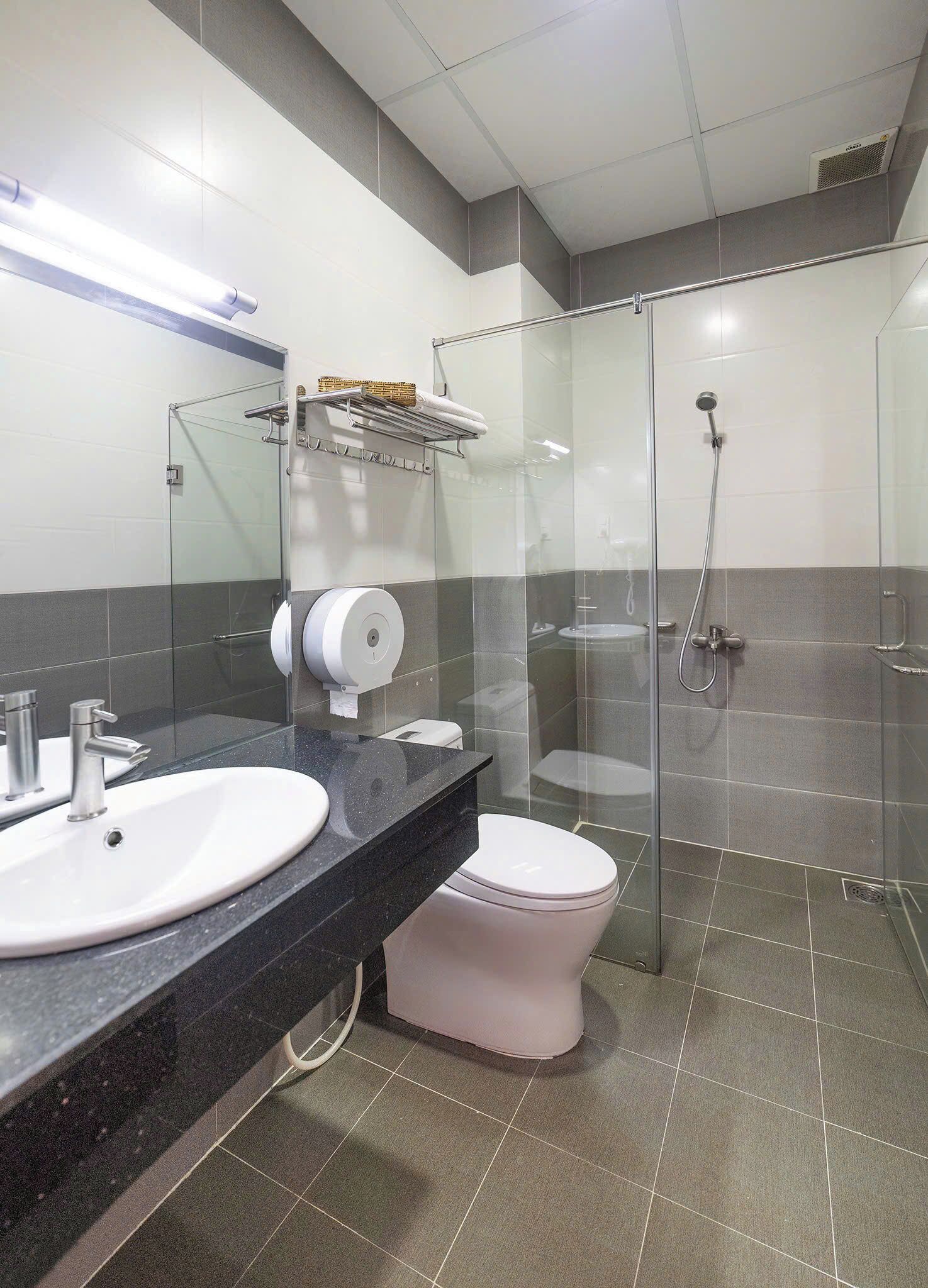 A modern bathroom with a glass-enclosed shower, a white sink, and a toilet.