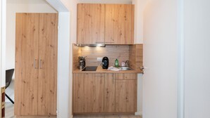 A compact kitchen with wooden cabinets and a stainless steel range hood.
