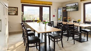 A dining area with a long table, multiple chairs, and a television mounted on the wall.