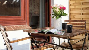 A wooden table with a magazine, a black mug, and a vase with flowers.