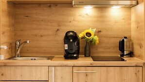 A kitchen with wooden cabinets, a Bosch coffee maker, a vase with sunflowers, and a coffee press.