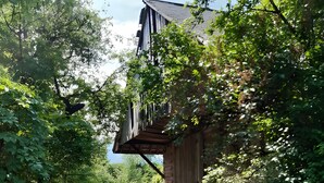 A narrow road flanked by dense greenery and a rustic building with a sloped roof.