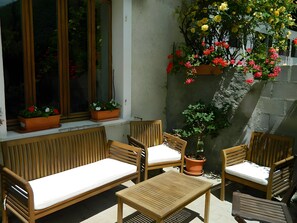 Eine Terrasse mit Holzmöbeln, darunter eine Couch und Stühle, und mit Kübelpflanzen.
