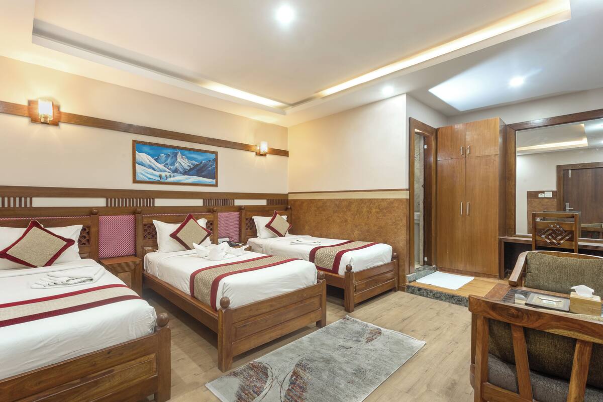 Una habitación de hotel con tres camas de madera, un escritorio de madera y un armario grande.