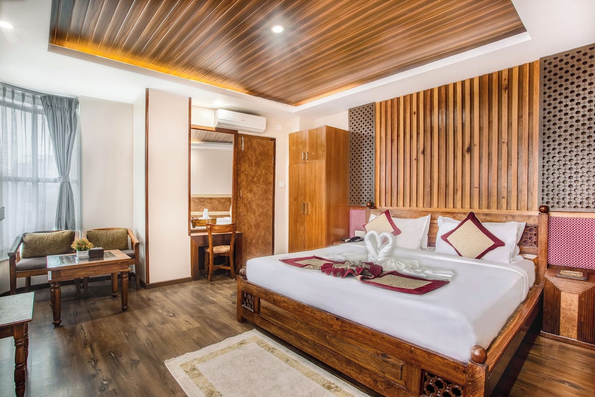 Una habitación de hotel con una cama de madera, un escritorio, una silla y un armario.