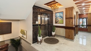 A modern lobby with a marble reception desk, an elevator, wooden accents, and a chandelier. - Royal Boutique Hotel (Kathmandu)