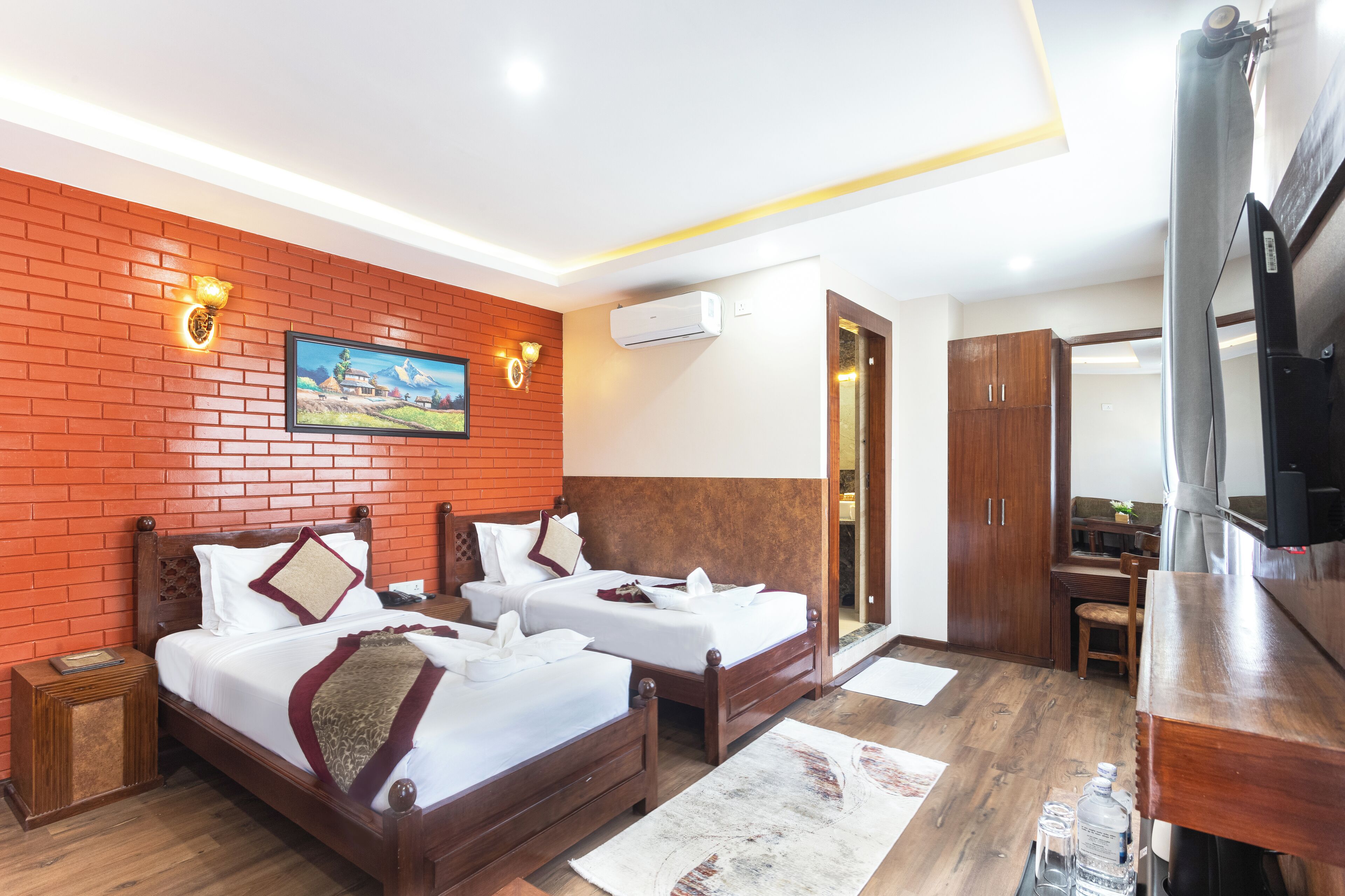 Habitación de hotel con dos camas, un televisor y un escritorio de madera.