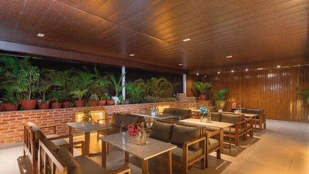 A restaurant with wooden tables and chairs, brick walls, and potted plants. - Royal Boutique Hotel (Kathmandu)