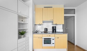 A modern kitchen with white and beige cabinetry, a built-in oven, and a coffee maker. - Wikingturm 20.4 - 20th Floor, 1 Room, View of the Schlei, Underground Parking (Schleswig)