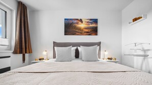 A neatly made bed with a quilt, a bedside table with a lamp, and a wall-mounted shelf.