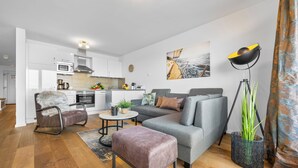 A modern living room with a grey sofa, a brown leather chair, a small coffee table, and a large floor lamp.