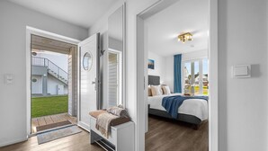Un interior moderno con un dormitorio que incluye una cama, un banco con alfombra y vistas a un patio trasero con una escalera.