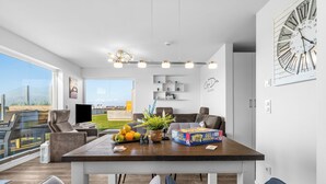 Una sala de estar moderna con comedor, ventanas grandes y vista a la ciudad.