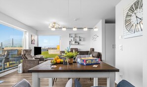 A modern living room with a dining area, large windows, and a view of the city.