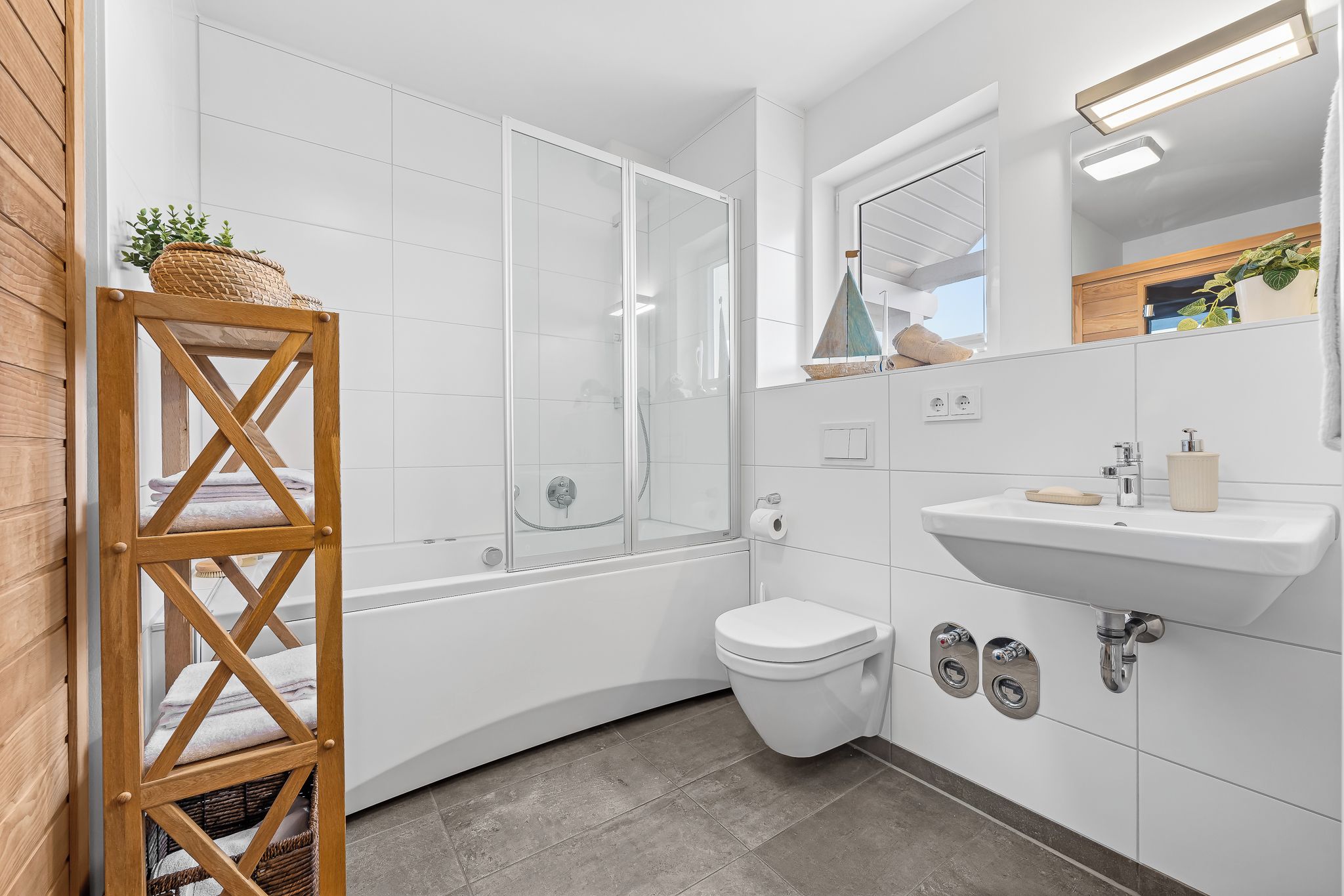 A modern bathroom with a glass shower enclosure, a white toilet, and a sink with a mirror above it.