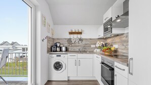 A compact kitchen with a washing machine, a microwave, and a stove.