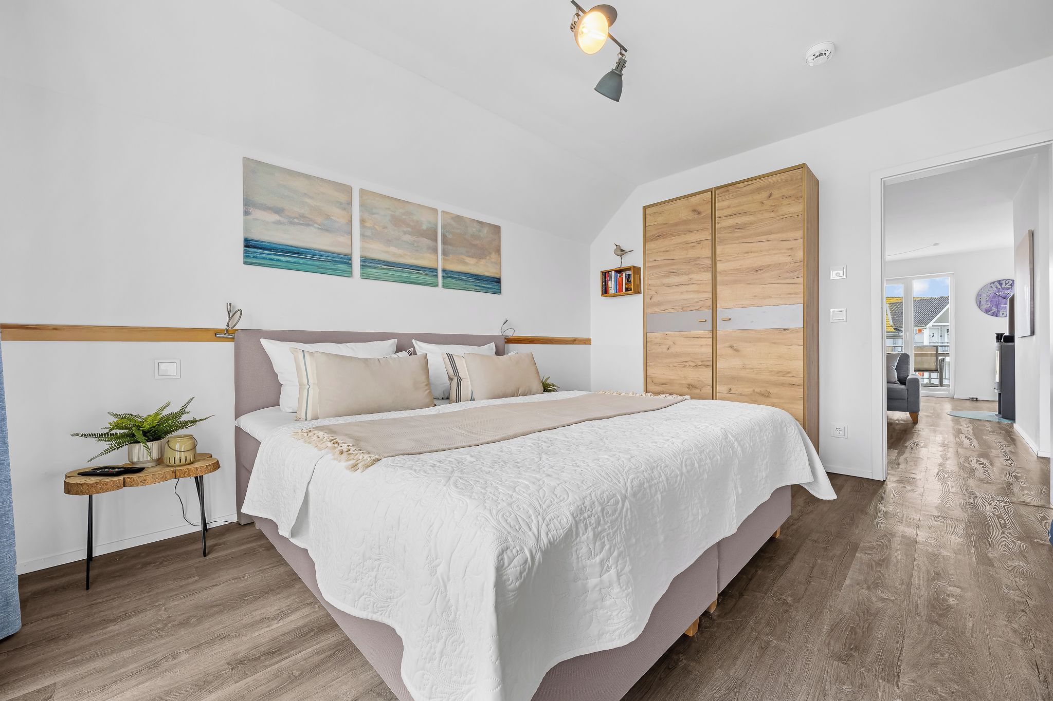 Une chambre à coucher avec un lit, une table de chevet et une œuvre d’art accrochée au mur.