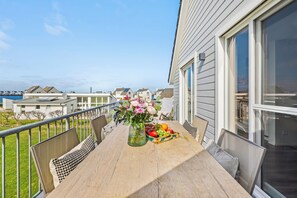 A balcony with a table, a vase of flowers, and a fruit basket.