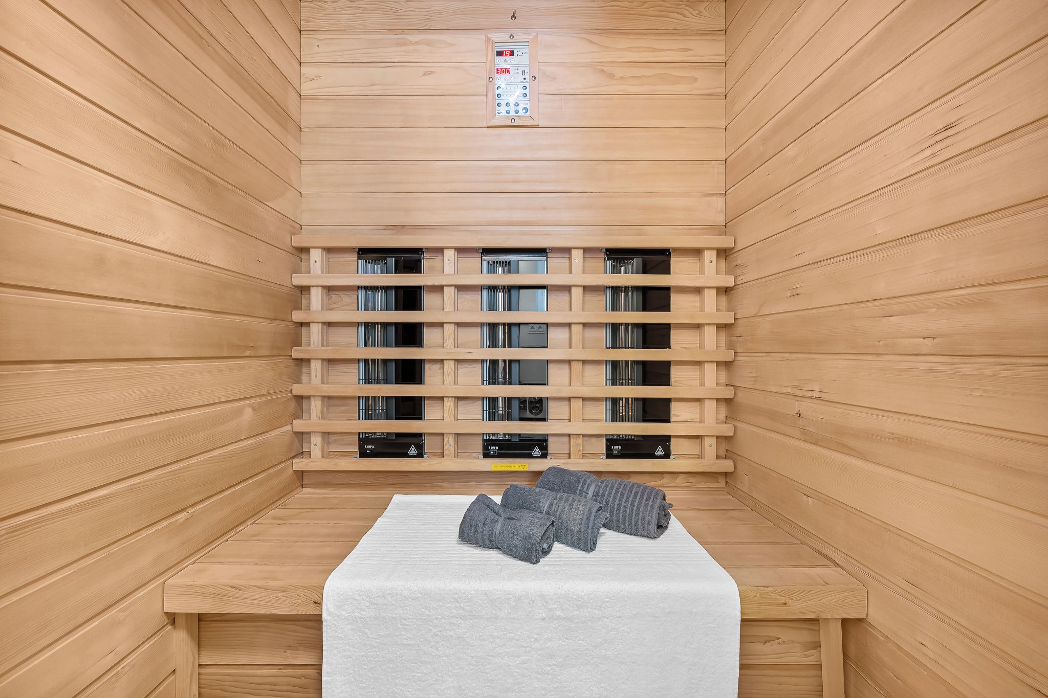 Un sauna avec des murs en bois, un banc et plusieurs autres bancs équipés de systèmes de chauffage.